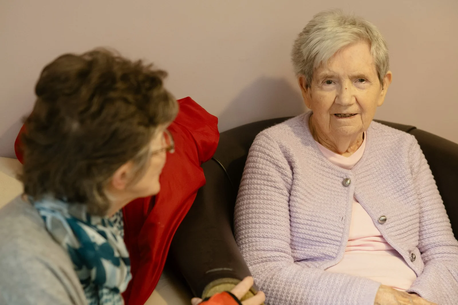 Two older women enjoying friendly conversation at home